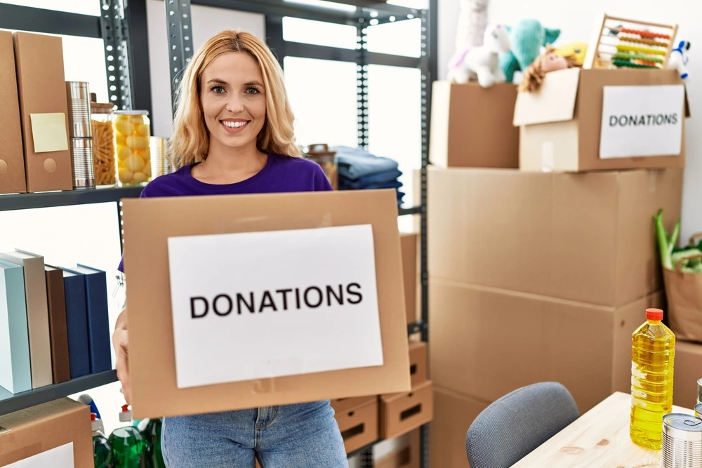 Lady working in a charity shop collecting donations | Swoosh Finance